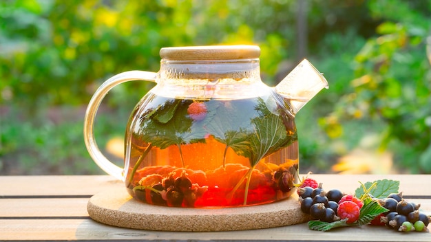Tè alla bacca preparato in una teiera di vetro trasparente su uno sfondo naturale