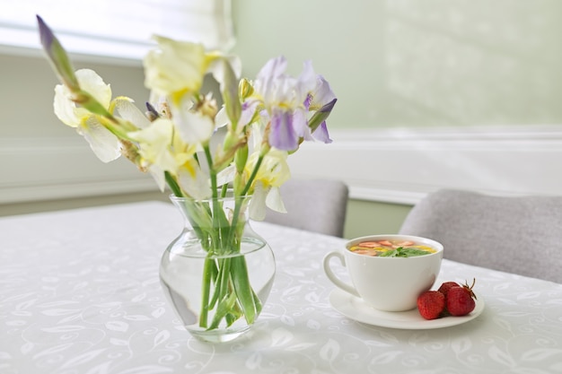 Tè alla fragola con bacche di limone alla menta sul primo piano del tavolo. Tavolo vicino alla finestra con vaso di fiori di iris