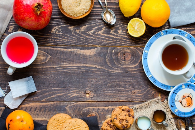 Tè alla frutta con limone, latte, miele, arancia, melograno, su uno sfondo di legno