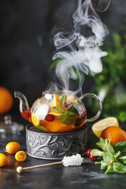 Tè alla frutta con menta, arance e mirtilli rossi su priorità bassa di pietra scura. Una tazza di tè caldo