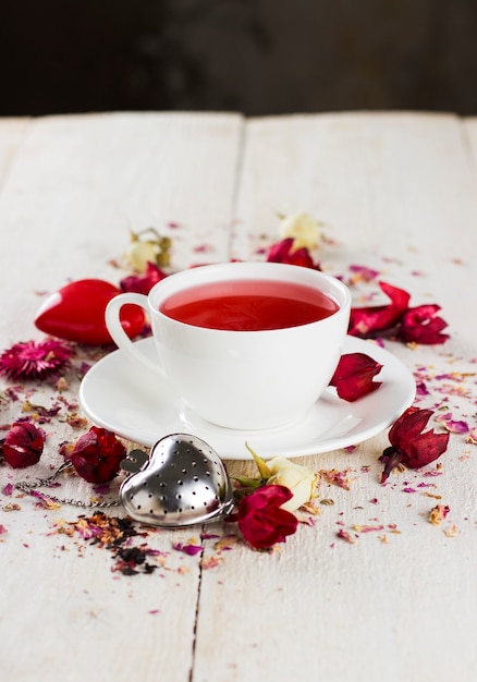 Tè alla frutta con una rosa in una tazza bianca