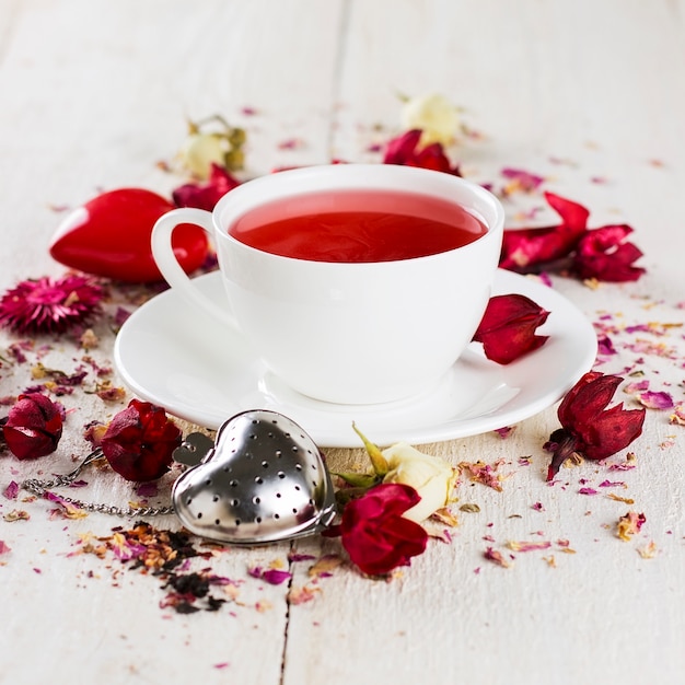 Tè alla frutta con una rosa in una tazza bianca
