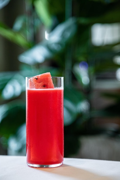 Tè alla frutta rossa o bevanda fredda all'anguria Bicchiere rosso dolce freddo per feste su sfondo rosa