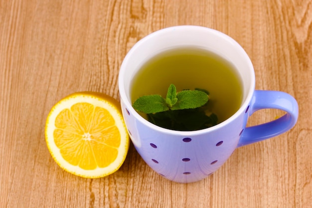 Tè alla menta con foglia di menta e limone su sfondo di legno