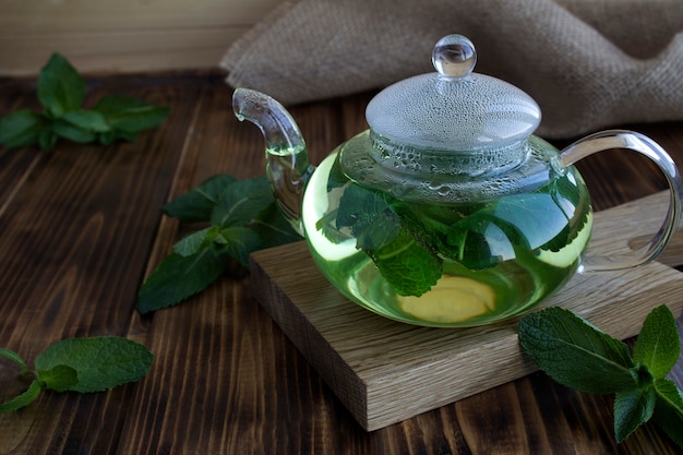 Tè alla menta nella teiera di vetro sul tavolo in legno rustico. Bevanda salutare. Avvicinamento.