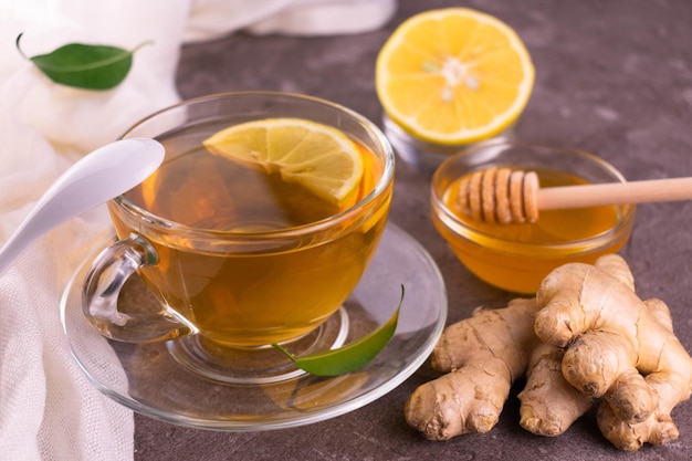 Tè allo zenzero con limone e miele in una tazza trasparente.