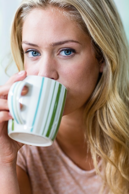 Tè bevente della donna bionda graziosa nella cucina