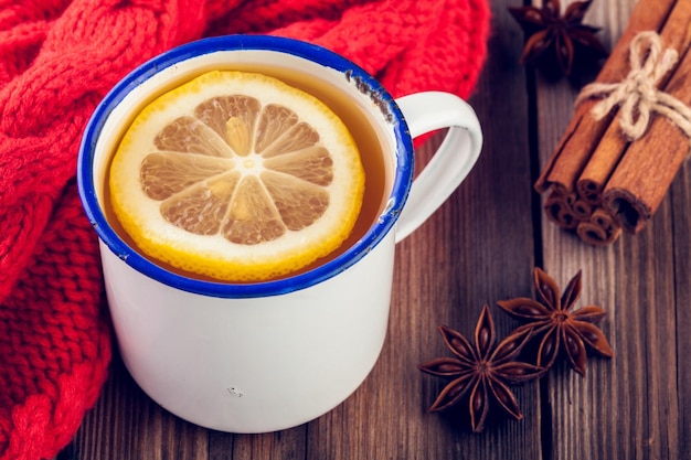 Tè caldo al limone in una tazza rustica con cannella e anice