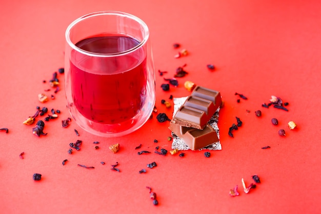 Tè caldo all'ibisco in un bicchiere trasparente con doppio fondo su fondo rosso