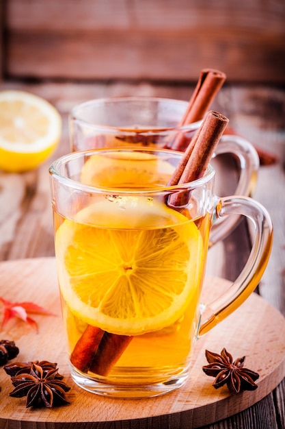 Tè caldo con anice al limone e cannella in tazze di vetro sulla tavola di legno