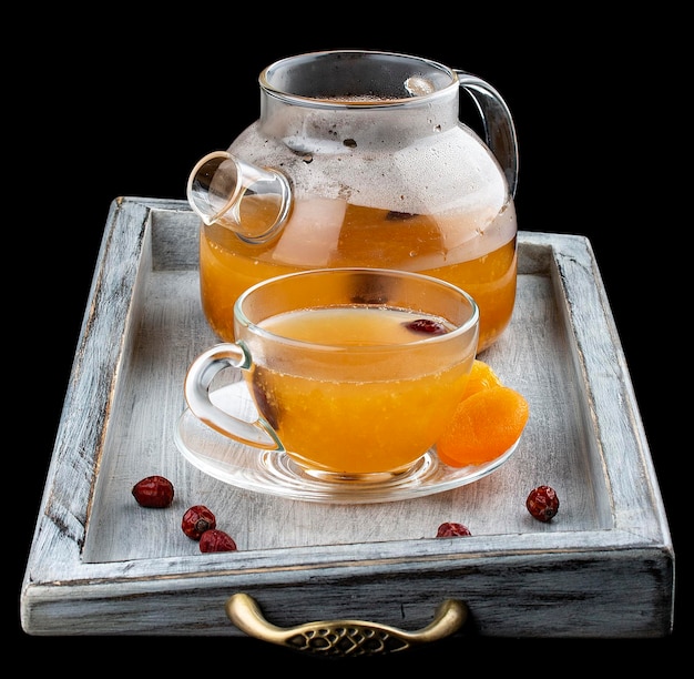Tè caldo con arancia e limone in una teiera di vetro su sfondo scuro