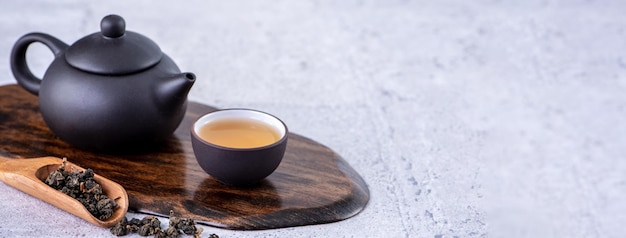 Tè caldo in teiera nera e tazze e foglie di tè secche su sfondo di cemento grigio brillante primo piano concetto di design dello spazio della copia