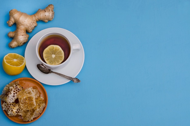 Tè con radice di limone, miele e zenzero su uno sfondo blu con spazio di copia, vista dall'alto. Prevenzione del raffreddore, per migliorare l'immunità in autunno e in inverno.
