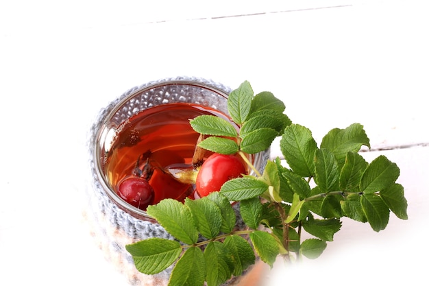 Tè con rosa canina e foglie di legno sfondo bianco vitamina c inverno autunno a maglia Tazza