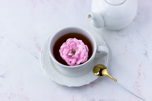 Tè con rosa tea in una tazza bianca su un tavolo di marmo bianco