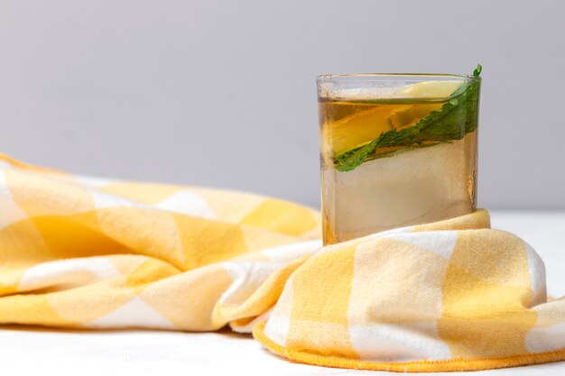 Tè con spicchi di ghiaccio, menta e limone sul tavolo bianco