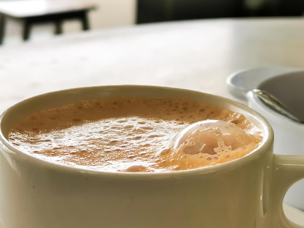 Tè con vista dall'alto con latte in una tazza popolarmente conosciuta come Teh Tarik sul tavolo.