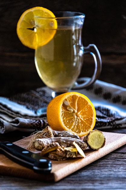 Tè con zenzero e limone sul tavolo da pranzo. Limone e zenzero su un tagliere.