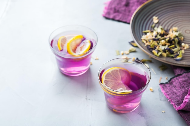 Tè di fiori di pisello di farfalla viola in un bicchiere sul tavolo