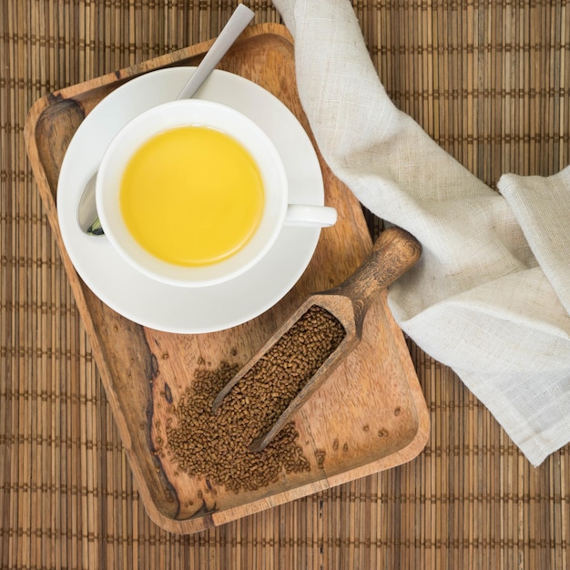 Tè di grano saraceno nella tazza bianca e tè di grano saraceno infuso su una stuoia marrone Tè Ku Qiao Superfood