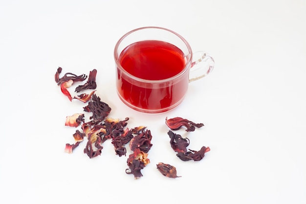 Tè di ibisco rosso in una tazza e fiori di ibisco essiccati