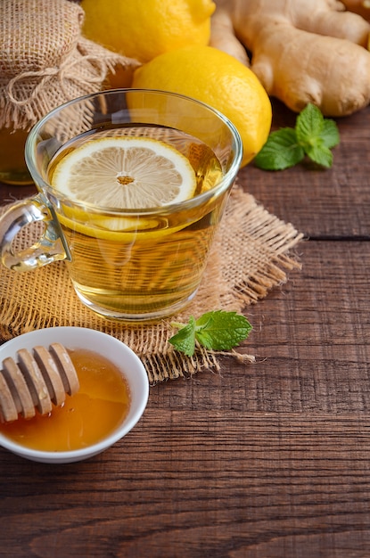 Tè di radice di zenzero con limone e miele sul tavolo di legno.