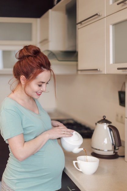 Tè di versamento sorridente della donna incinta