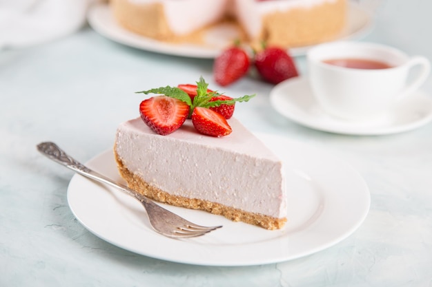 Tè dolce per la colazione e deliziosa torta di formaggio con fragole fresche e menta ricetta fatta in casa senza cottura su un tavolo di pietra blu Copia spazio