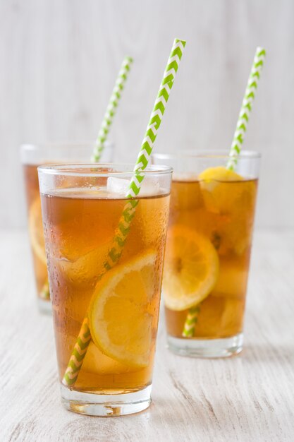 Tè freddo rinfrescante con il limone sulla tavola di legno bianca