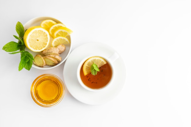 Tè fresco con limone e miele su uno sfondo bianco