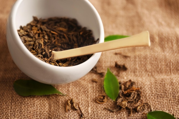 Tè granulato con foglie verdi su sfondo sacco