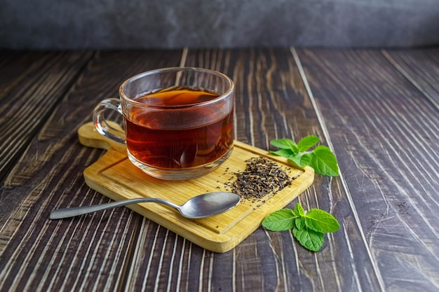 Tè in tazza di vetro su fondo di legno