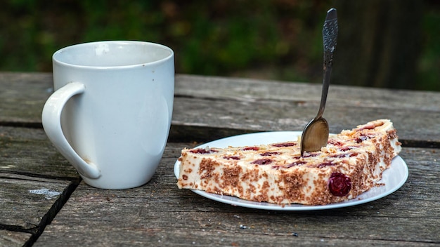 Tè in una tazza bianca su un tavolo di legno accanto a una torta di mele su un piatto bianco