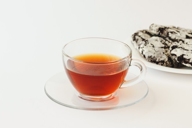Tè in una tazza di vetro e biscotti fatti in casa su sfondo bianco
