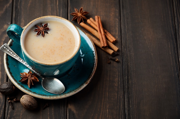 Tè indiano masala chai. Tè aromatizzato al latte sul tavolo di legno scuro.