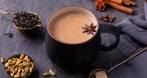 Tè indiano masala con latte e spezie in tazza Sfondo grigio Primo piano