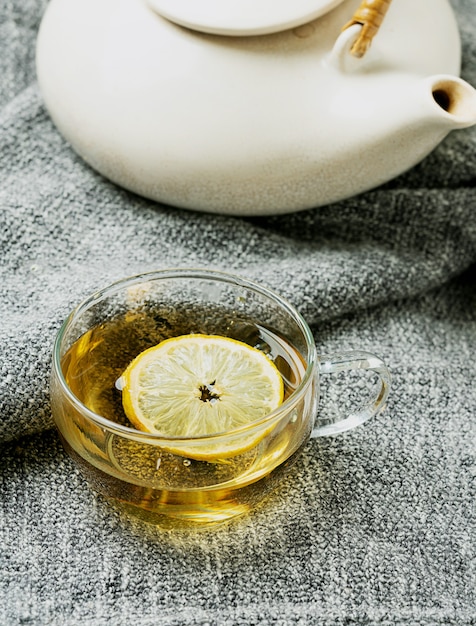 Tè Lemon Verbena servito con limone su una coperta grigia con teiera vintage. Avvicinamento