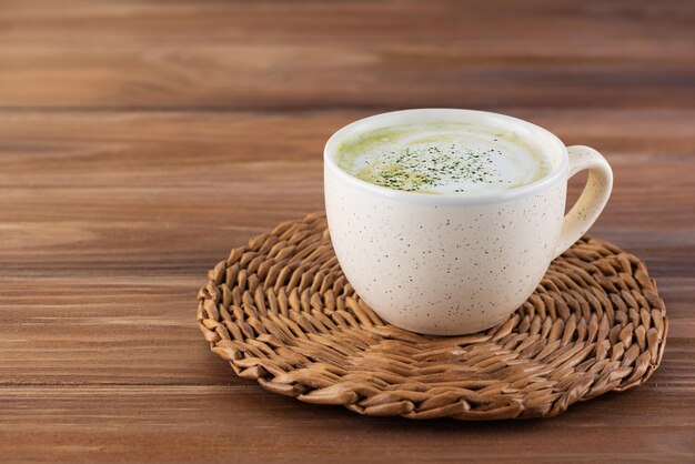 Tè Matcha latte con latte di cocco e semi di canapa in una tazza su un tavolo di legno.