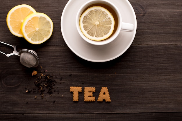 Tè nero con tè al limone e biscotti su un tavolo di legno