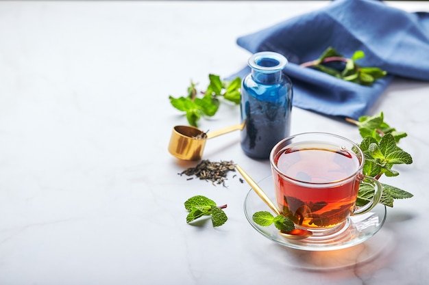 Tè nero in tazza di vetro trasparente con foglie di menta tè lenitivo antistress