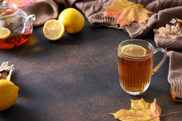 Tè nero riscaldante al limone in uno stile di vita accogliente con foglie autunnali e sciarpa accogliente