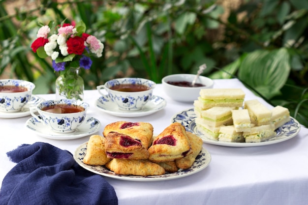 Tè pomeridiano in giardino con focaccine, marmellata di fragole, tramezzini con insalata di cetrioli e uova.