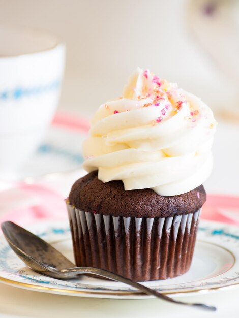 Tè pomeridiano servito con un cupcake bianco.