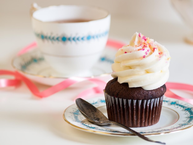 Tè pomeridiano servito con un cupcake bianco.