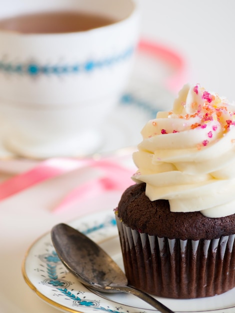 Tè pomeridiano servito con un cupcake bianco.