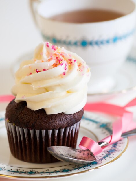 Tè pomeridiano servito con un cupcake bianco.