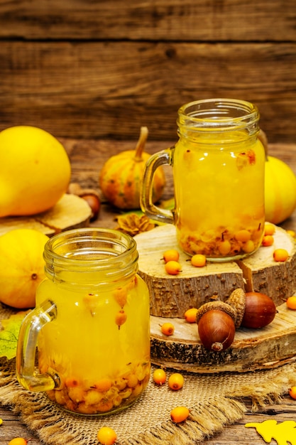 Tè salutare vitaminico all'olivello spinoso in vasetti di vetro con frutti di bosco freschi