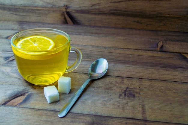 Tè verde al limone in una tazza di vetro zucchero e un cucchiaio