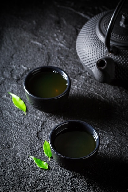 Tè verde fresco in tazza da tè su roccia nera