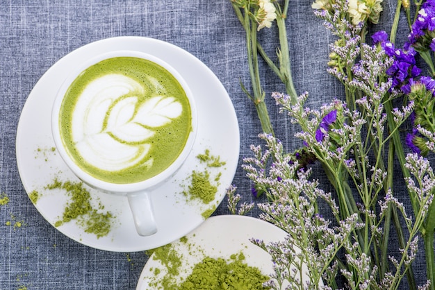 Tè verde / latte matcha in una tazza con polvere di matcha sul tavolo